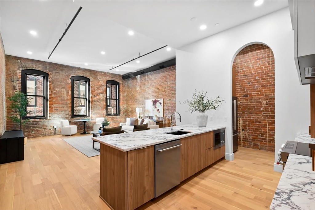 Open concept loft with kitchen island, marble counters, and living area